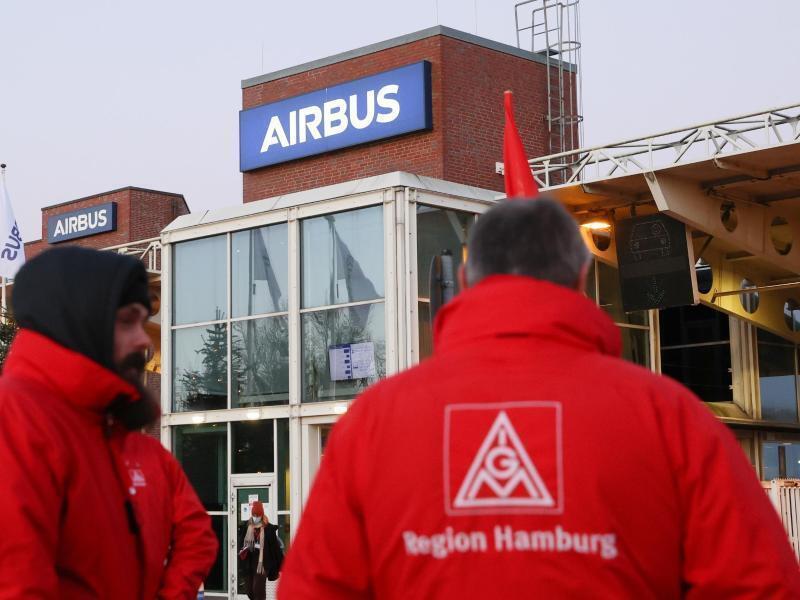 Airbus: Keine Kündigungen bis 2030 – Freude in Betrieben groß Mitglieder der IG Metall stehen im Dezember 2021 vor einem Werkstor von Airbus in Hamburg. Foto: Bodo Marks/dpa/Archivbild