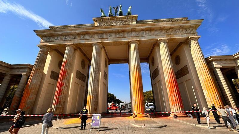Mitglieder der Klimaschutzgruppe Letzte Generation sprühen im September das Brandenburger Tor mit oranger Farbe an.