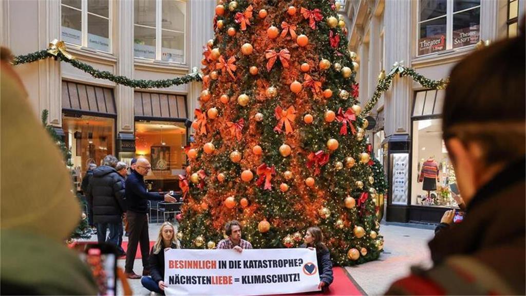 Mitglieder der Protestgruppe Letzte Generation sitzen vor einem mit Farbe besprü...
