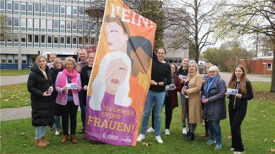 Mitglieder des Netzwerks gegen häusliche Gewalt hissen die erste Flagge vor dem Winsener Kreishaus.
