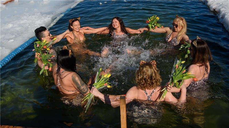 Mitglieder eines Winterschwimmclubs feiern in einem Eisloch den Internationalen Frauentag.