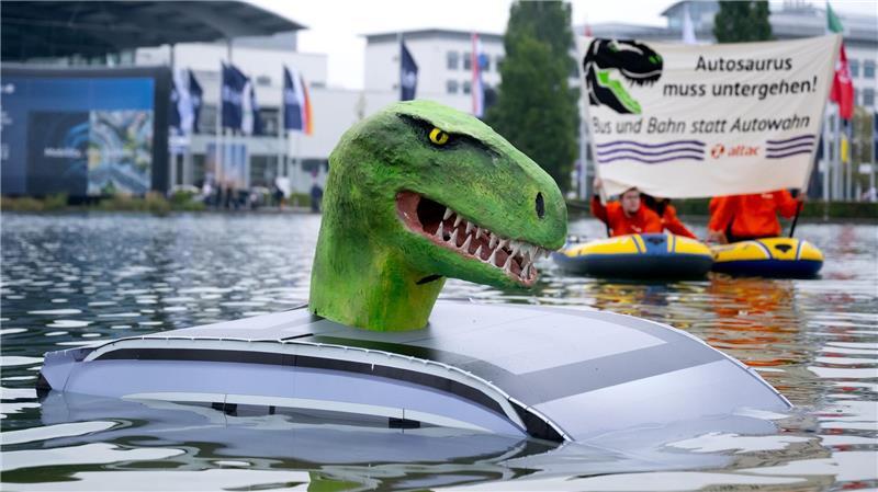 Mitglieder von Attac demonstrieren vor der Eröffnung der Internationalen Automobil-Ausstellung (IAA Mobility) in München mit einem „Autosaurus“ für eine Mobilitätswende.