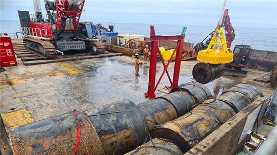 Mithilfe des Elektromagneten (gelb) werden die Stahlrollen aus dem Laderaum des Schiffes geborgen.