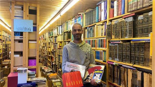 VHS-Mitarbeiter Tobias Rothenberg zwischen den Bücherregalen von Hans-Uwe Hansens ehemaliger Privatbibliothek