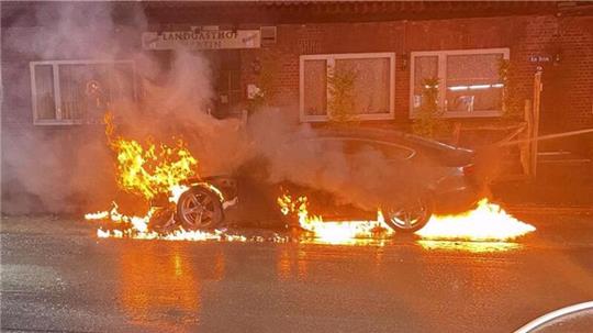 Feuerwehrleute stehen vor dem ausgebrannten Audi.