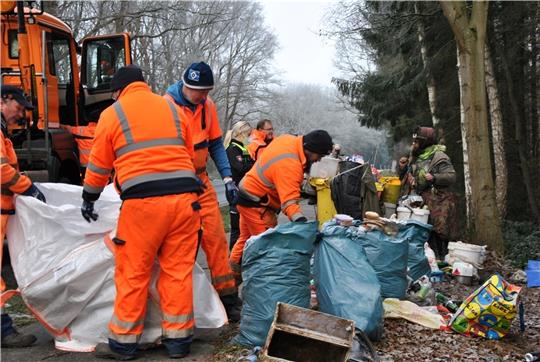 Müllabfuhr beim Obdachlosen an der B 73 : Mitarbeiter der Straßenmeisterei packen seine Müllsäcke in einen weißen Sack. Foto: Lohmann