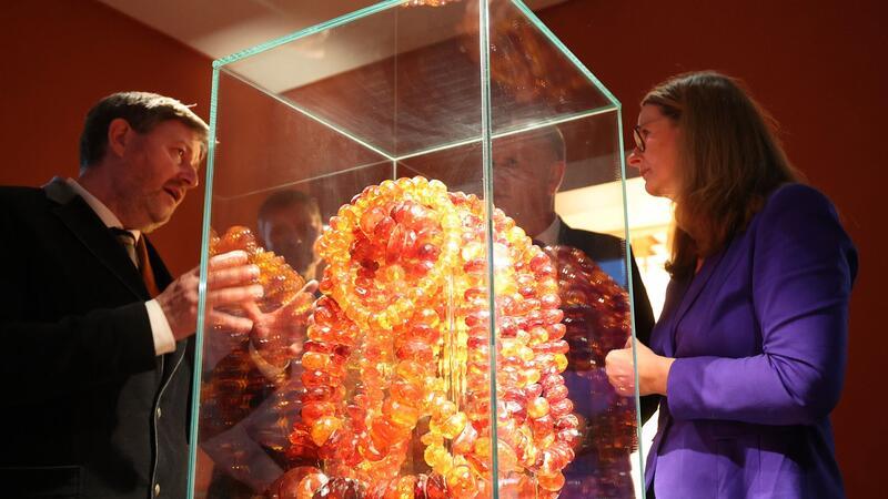Ribnitz-Damgarten erwirbt Bernstein-Kunstsammlung Museumsleiter Axel Attula (l-r) und Kulturministerin Bettina Martin betrachten das Exponat „Wasserfall“ oder „Goldener Kettenberg“.
