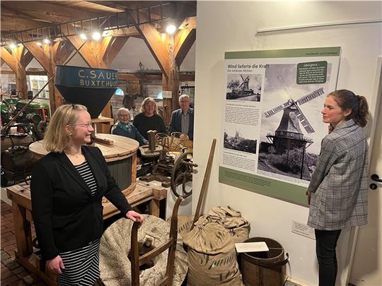 Museumsleiterin Dr. Kai Janofsky hängt mit Kollegin Pauline Wetegrove die Mühlen-Tafel auf. Catriona Wesselhöft, Birgit Behrens und Bürgermeister Matthias Riel schauen zu. Die 18 neuen Info-Tafeln sind ein erster Baustein für eine Neukonzep