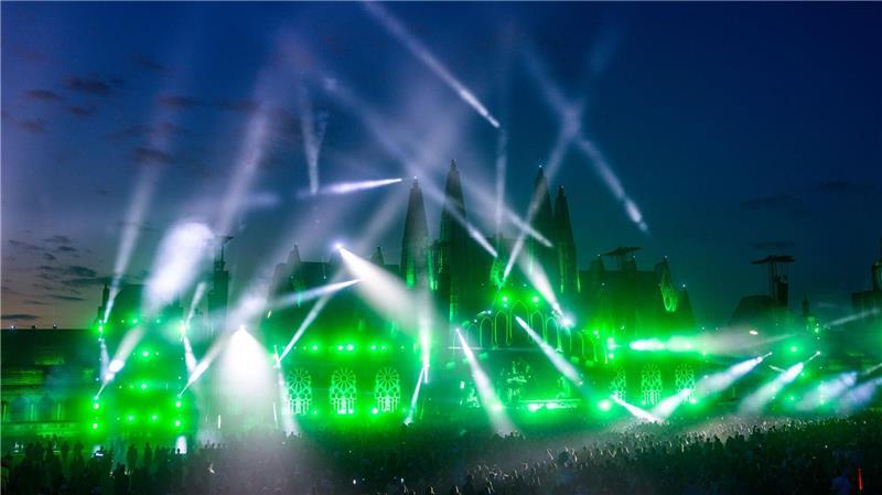 Musikfans tanzen nach Sonnenuntergang vor der Hauptbühne des Airbeat One Festivals. Zu dem Elektromusik-Festival werden bis zum 13.07.2025 etwa 200.000 Elektrofans erwartet.