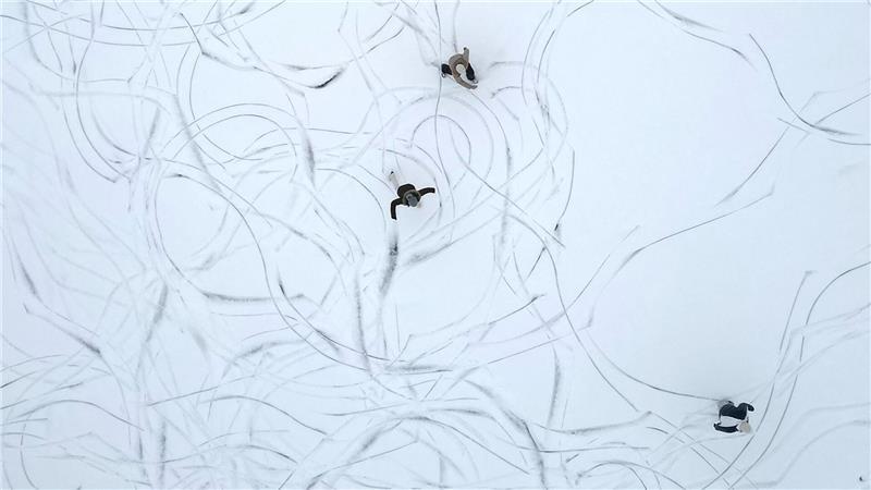 Muster im Schnee: Eine Luftaufnahme zeigt Schlittschuhläufer auf einem zugefrorenen See in Österreich.