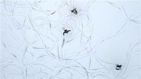 Muster im Schnee: Eine Luftaufnahme zeigt Schlittschuhläufer auf einem zugefrorenen See in Österreich.