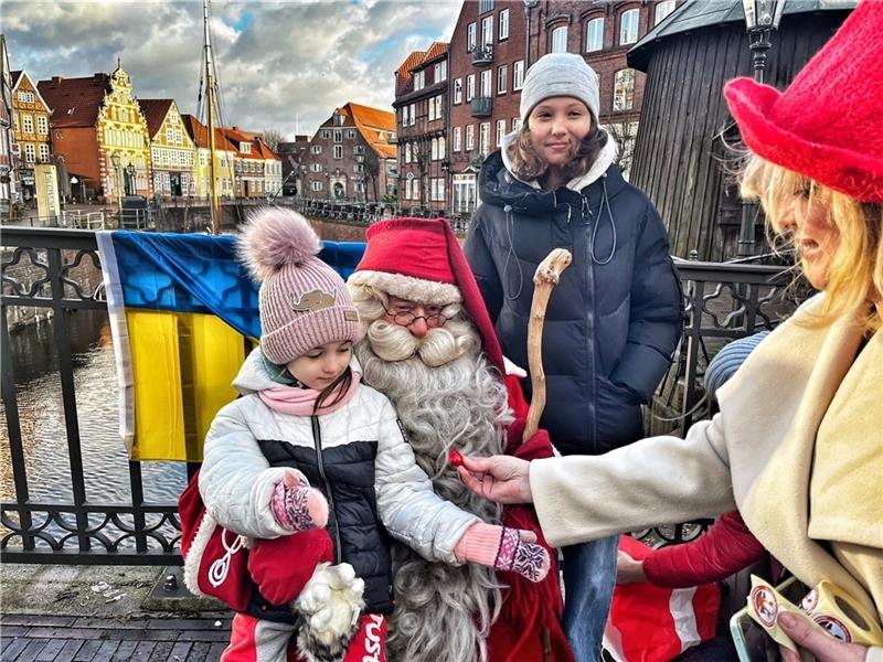 Nach dem Foto mit dem Weihnachtsmann aus Lappland bekommen die fünfjährige Arina und ihre 13-jährige Schwester Sofiia noch ein Schokoladenherz von seiner Helferin geschenkt: Dr. Kateryna Savytska und ihre Gruppe haben die Aktion organisiert