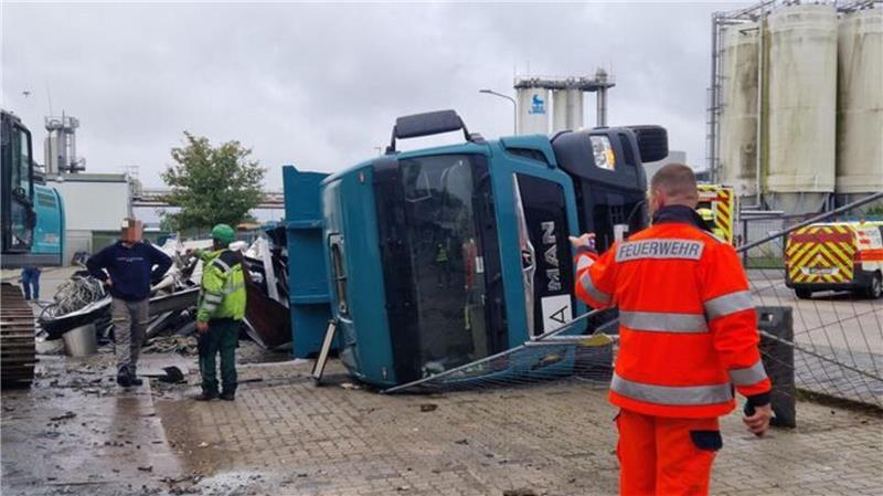 Ein Feuerwehr-Mann begutachtet die Lage eines umgestürzten Lkws im Hafen von Cuxhaven.