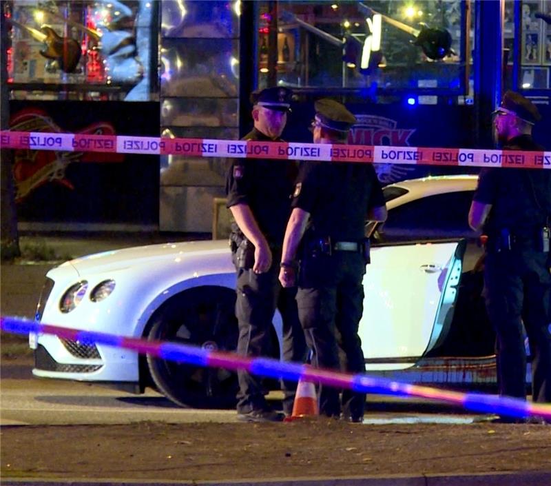 Nach dem Schuss auf den Fahrer eines weißen Luxuswagens: Polizisten stehen neben dem Auto auf dem Millerntorplatz. Foto Güler/dpa