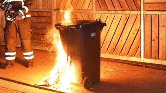Einsatzkräfte der Stader Feuerwehr löschen eine brennende Mülltonne.