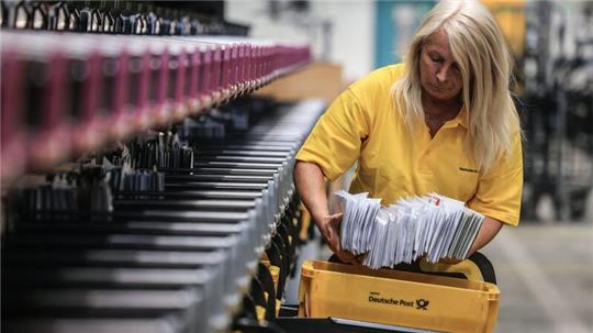 Eine Mitarbeiterin der Post sortiert Briefe.