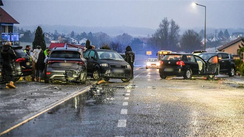 Unzählige Glatteisunfälle im Süden Deutschlands Nach einem Unfall bei Glatteis mit mehreren Fahrzeugen in Baden-Württemberg stehen Helfer und Beteiligte an den Autos auf einer Straße.