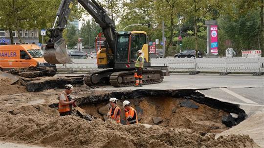 Nach einem Wasserrohrbruch in Hamburg in der Amsinckstraße arbeiten Bauarbeiter in einem Loch.