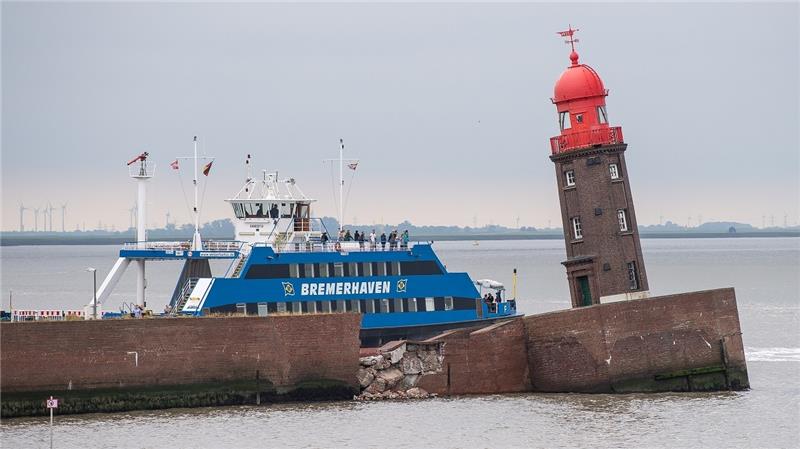 Nach mehrstündiger Sperrung fährt die erste Fähre am schief stehenden Moleturm vorbei. Teile der Nordmole in Bremerhaven sind in der Nacht zum Donnerstag eingesackt. Die Einfahrt zur Geeste ist gesperrt. Auch der Fährbetrieb der Weserfähre musste zeitweise eingestellt werden. Foto: Sina Schuldt/dpa