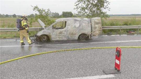 Ein Feuerwehrmann steht neben dem ausgebrannten Ford.