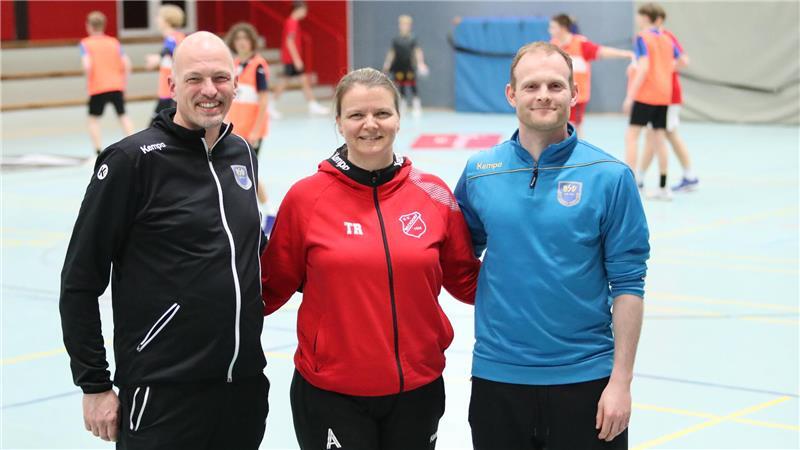 Karsten von Eitzen, Nadine Völkers und Jonathan Pape stehen in einer Sporthalle umarmen sich und lächeln.