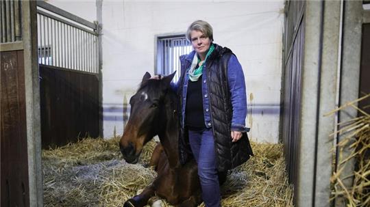 Nadine Wilkens, Landwirtin und Inhaberin einer Pferdepension, steht neben einem ihrer Pferde.