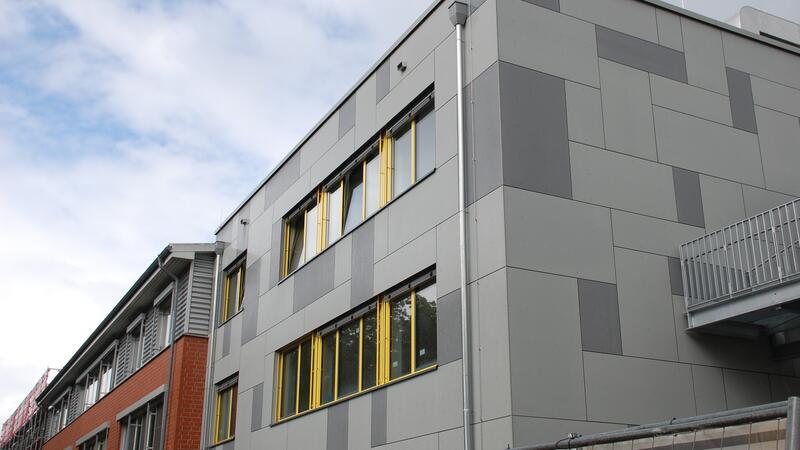 Ferien bald vorbei: Wird der Anbau am Aue-Geest-Gymnasium rechtzeitig fertig? Nahtlos ans Schulgebäude angebaut - aber optisch setzt sich der neue Anbau mit grauer Fassade und gelben Fensterrahmen ab.