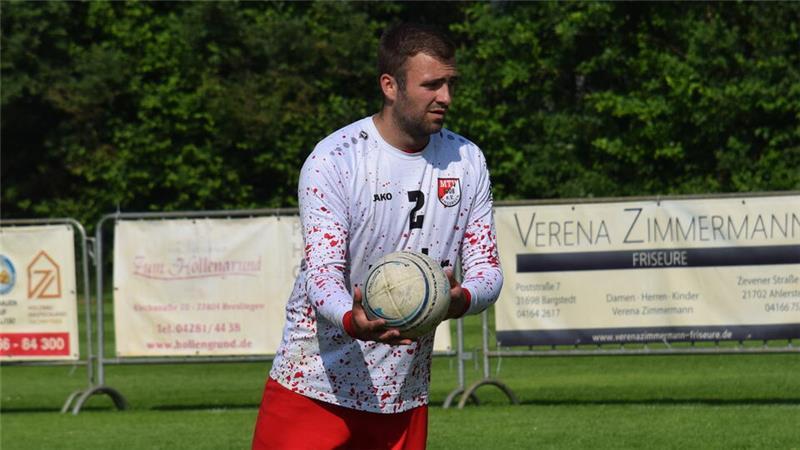 Düdenbüttel feiert Befreiungsschlag, Wangersen einen Rückkehrer Nick Poppe vom MTV Wangersen mit weißem Langarmshirt und roter Hose hält einen Faustball in der Hand.