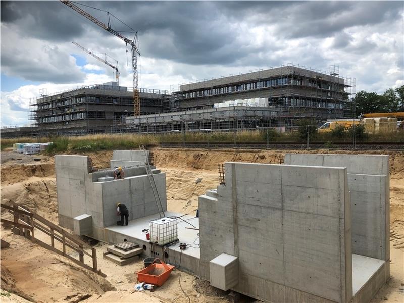 Neben dem Gleis, das entlang der neuen Bildungscampus-Gebäude verläuft, haben die Spezialisten die massiven Fundamente gebaut, die die neue Stahlbrücke tragen werden. Ist die neue Brücke mit Widerlagern und Überbau komplett, wird sie durch 