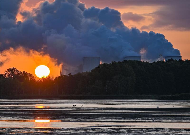 Neben den Kühltürmen des Braunkohlekraftwerks Jänschwalde in Brandenburg geht die Sonne auf - noch unter den Dampfwolken.