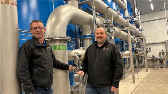 Netzmeister Thomas Bode (links) und Technischer Bereichsleiter René Back stehen in der Filterhalle des Wasserwerks Eilendorf. Die blauen Filterbehälter bereiten Grundwasser aus bis zu 160 Metern Tiefe zu Trinkwasser auf.