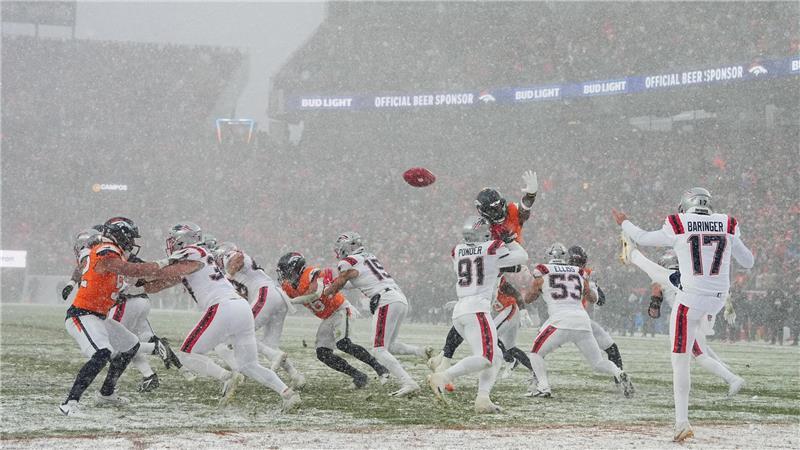 New England Patriots Punter Bryce Baringer (M) bei Schneefall in Aktion.