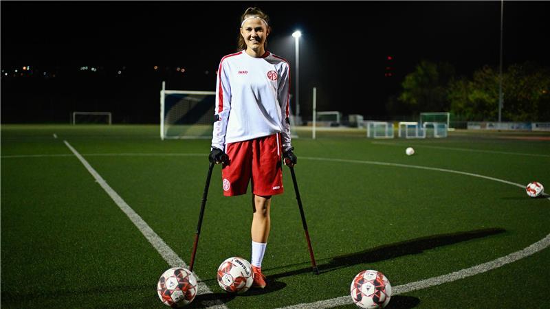 Nicola Roos, Amputierten-Fußballerin des 1. FSV Mainz 05, steht bei einem Training auf dem Sportplatz der Spielvereinigung Essenheim neben Fußbällen.