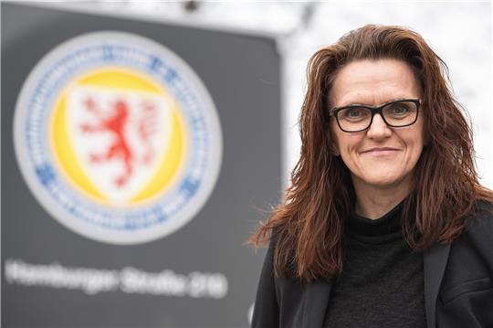 Nicole Kumpis steht vor dem Logo von Eintracht Braunschweig. Sie wurde am 16. März 2022 auf der Mitgliederversammlung zur neuen Präsidentin des Vereins gewählt. Foto: Swen Pförtner/dpa