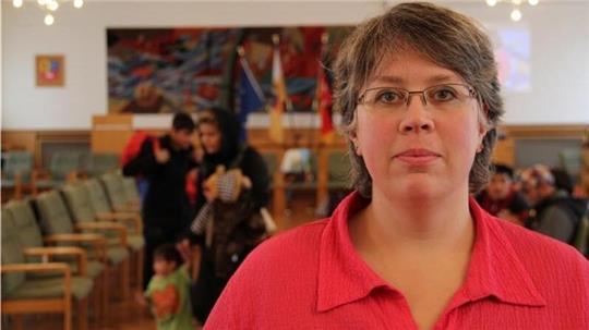 Nicole Streitz im Jahr 2015. Im Hintergrund sind der Kreistagssitzungssaal und einige Flüchtlinge zu sehen.