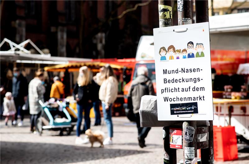 Niedersachsen, Oldenburg: Ein Schild mit der Aufschrift "Mund-Nasen-Bedeckungspflicht auf dem Wochenmarkt“ hängt vor einem Zugang zum Wochenmarkt in der Innenstadt. Foto: Hauke-Christian Dittrich/dpa