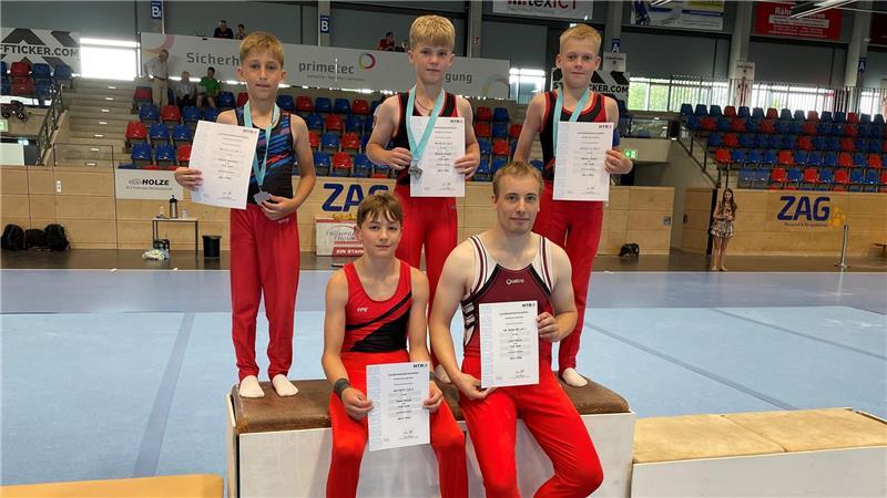 Drei Medaillen für den TuS Jork bei Landesmeisterschaften Drei Turner des TuS Jork sitzen auf einem Podest in einer Sporthalle, zwei sitzen dort drauf.