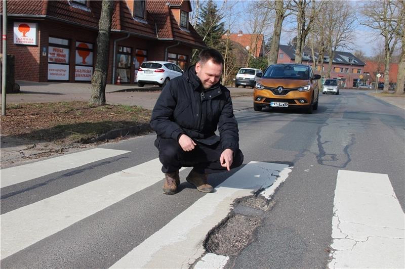 So gefährlich sind die Straßen in Moisburg Nils Bludau zeigt das rissige Loch im Zebrastreifen an der stark befahrenen Ortsdurchfahrt. Eine Stolperfalle nicht nur für die Kinder. Fotos: Michaelis