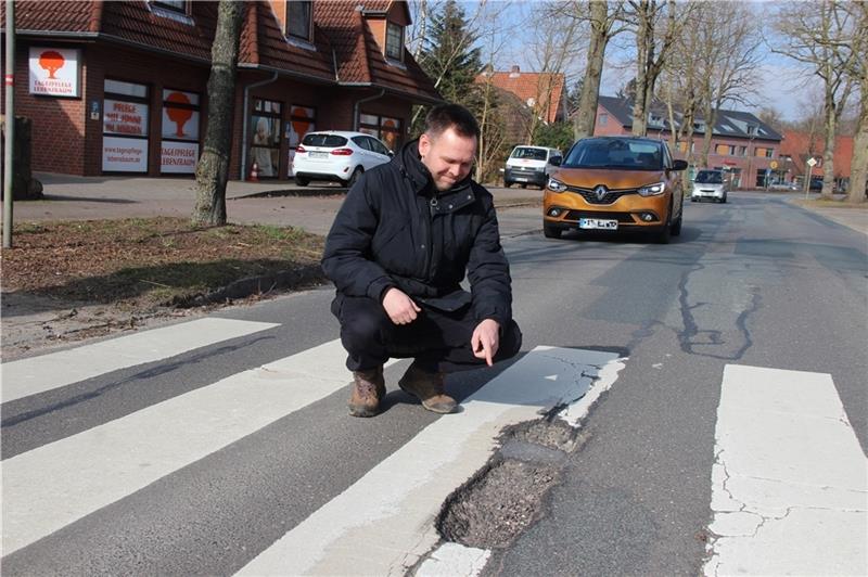 Nils Bludau zeigt das rissige Loch im Zebrastreifen an der stark befahrenen Ortsdurchfahrt. Eine Stolperfalle nicht nur für die Kinder. Fotos: Michaelis