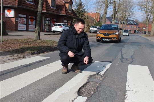 Nils Bludau zeigt das rissige Loch im Zebrastreifen an der stark befahrenen Ortsdurchfahrt. Eine Stolperfalle nicht nur für die Kinder. Fotos: Michaelis