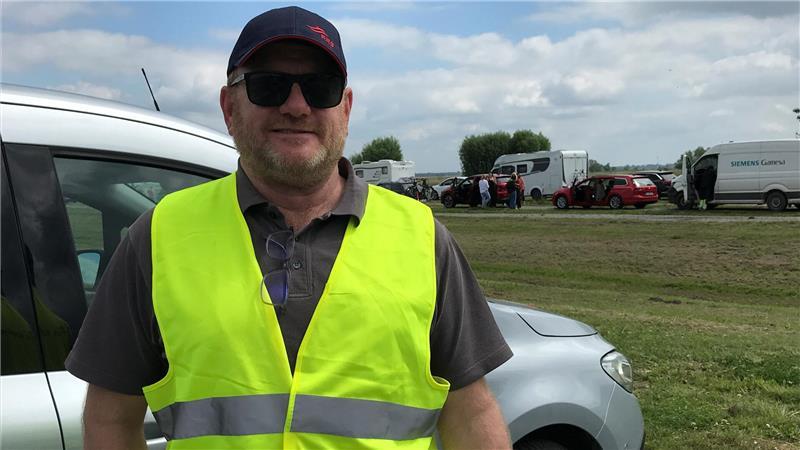 Fischbrötchen entschädigt: Pfingsturlaub startet mit Stau vor der Elbfähre Nils Hammann dirigiert die wartenden Autofahrer auf die richtige Spur. Er ist nautischer Leiter der FRS Elbfähre.