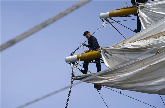 Noah Straßner (l), Toppsgast auf der „Gorch Fock“, und die Segelmannschaft holen die Segel des Segelschulschiffs «Gorch Fock» ein.