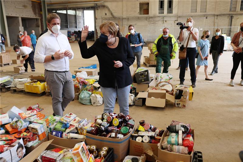 Nordrhein-Westfalen, Bad Münstereifel: Bundeskanzlerin Angela Merkel und Landrat Markus Ramers besichtigen ein Lager mit Lebensmitteln bei ihrem Besuch im vom Hochwasser betroffenen Gebiet von Bad Münstereifel. Foto: Oliver Berg/dpa