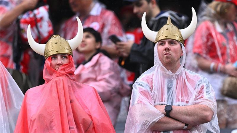 Norwegische Fans mit Regenschutz stehen vor dem Spiel im Stadion.