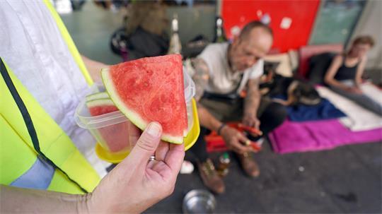 Obdachlose Menschen werden bei Hitze mit erfrischendem Obst unterstützt.