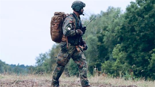 Oberst Maik Münzner nach einem Sprung und der Schirmabgabe, mit Sturmgepäck, Waffe und Funk auf dem Weg zum Sammelpunkt der Fallschirmjäger.