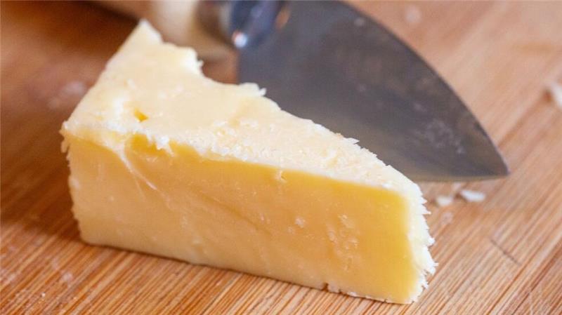 Öko-Test entdeckt Mineralöle in veganem Käse Ein Stück Käse liegt auf einem Brett.