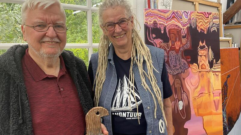 Michael Jalowczarz und Christa Donatius stehen vor den Fenstern des lichtdurchfluteten Ateliers mit Bildern der Malerein im Hintergrund