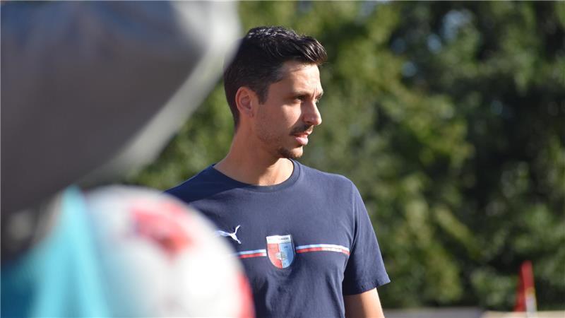 Oliver Ioannou steht am Seitenrand und schaut zum Spielgeschehen.