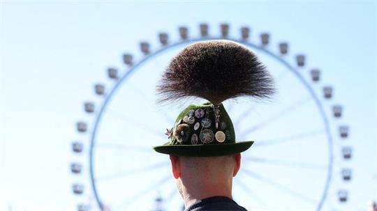 Oktoberfest 2026: ein Mann mit Gamsbart steht am ersten Wiesn Tag vor dem Riesenrad.